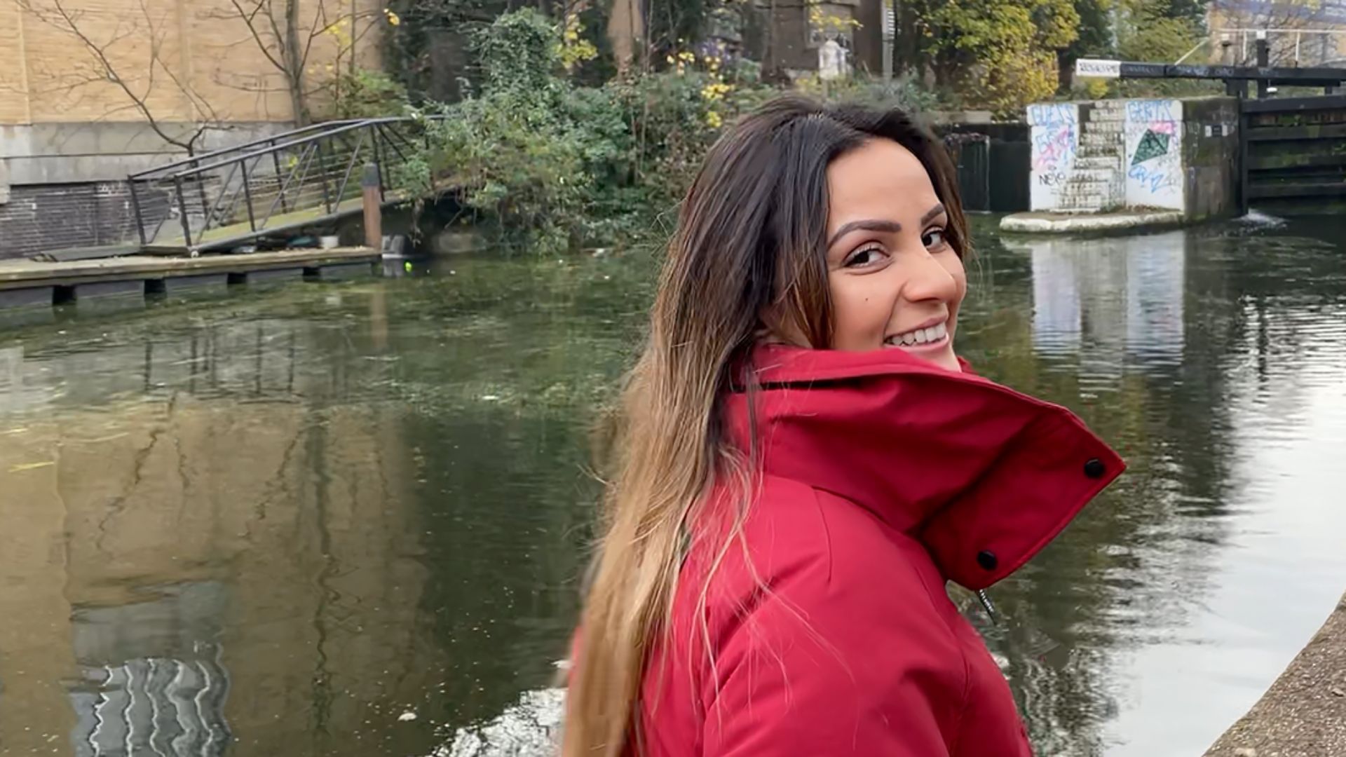 Eine Frau mit braunen Haaren und roter Jacke lächelt in die Kamera.