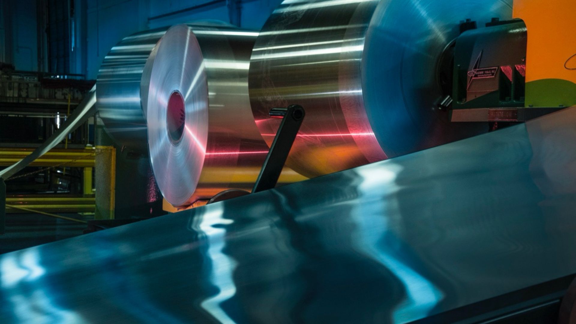 Eine Produktionsmaschine, in der Aluminium auf großen Rollen aufgewickelt ist und verarbeitet wird.