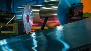 Eine Produktionsmaschine, in der Aluminium auf großen Rollen aufgewickelt ist und verarbeitet wird.