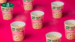 Sechs Töpfe mit Knorr-Fertiggerichten der Geschmacksrichtung Carbonara vor einem hellen, rosafarbenen Hintergrund.