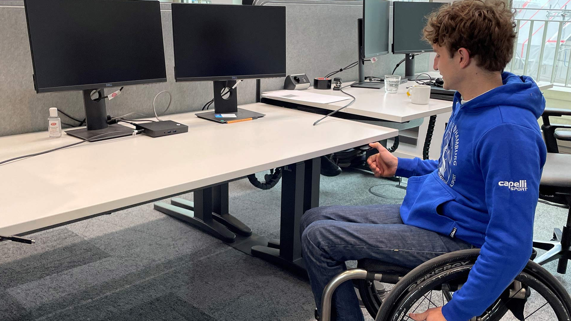 Ein Rollstuhlfahrer der BG Baskets testet einen höhenverstellbaren Schreibtisch in der Unilever-Zentrale in Hamburg.