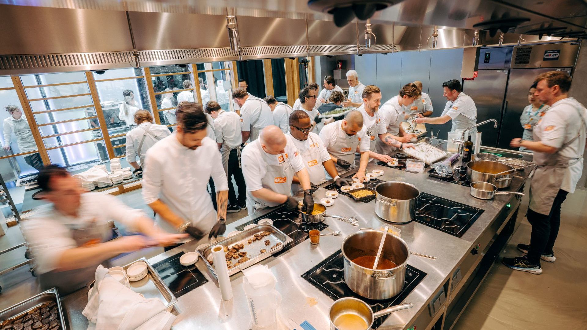 Ein Team von Unilever Food Solutions Köchen bereitet in einer lebhaften Küche Essen vor. Zahlreiche Töpfe stehen auf den Herdplatten.