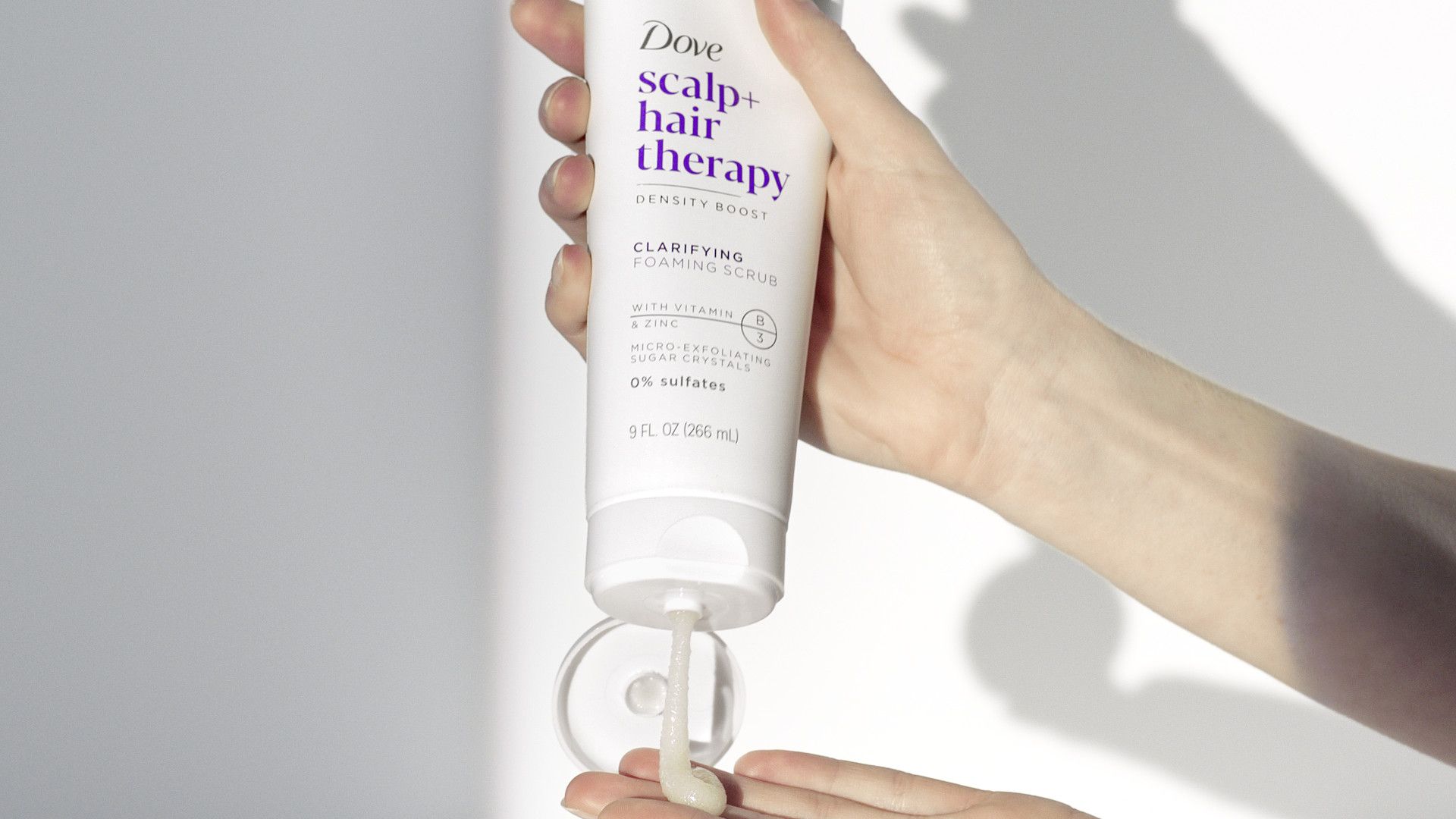 Weißes Produkt, das aus einer Dove-Behandlungsflasche für Kopfhaut- und Haar gepresst wird.