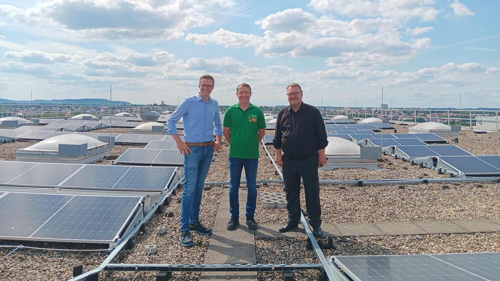 Drei Personen stehen auf dem Dach des Knorr-Hochregallagers zwischen Solarpanels.
