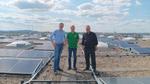 Drei Personen stehen auf dem Dach des Knorr-Hochregallagers zwischen Solarpanels.